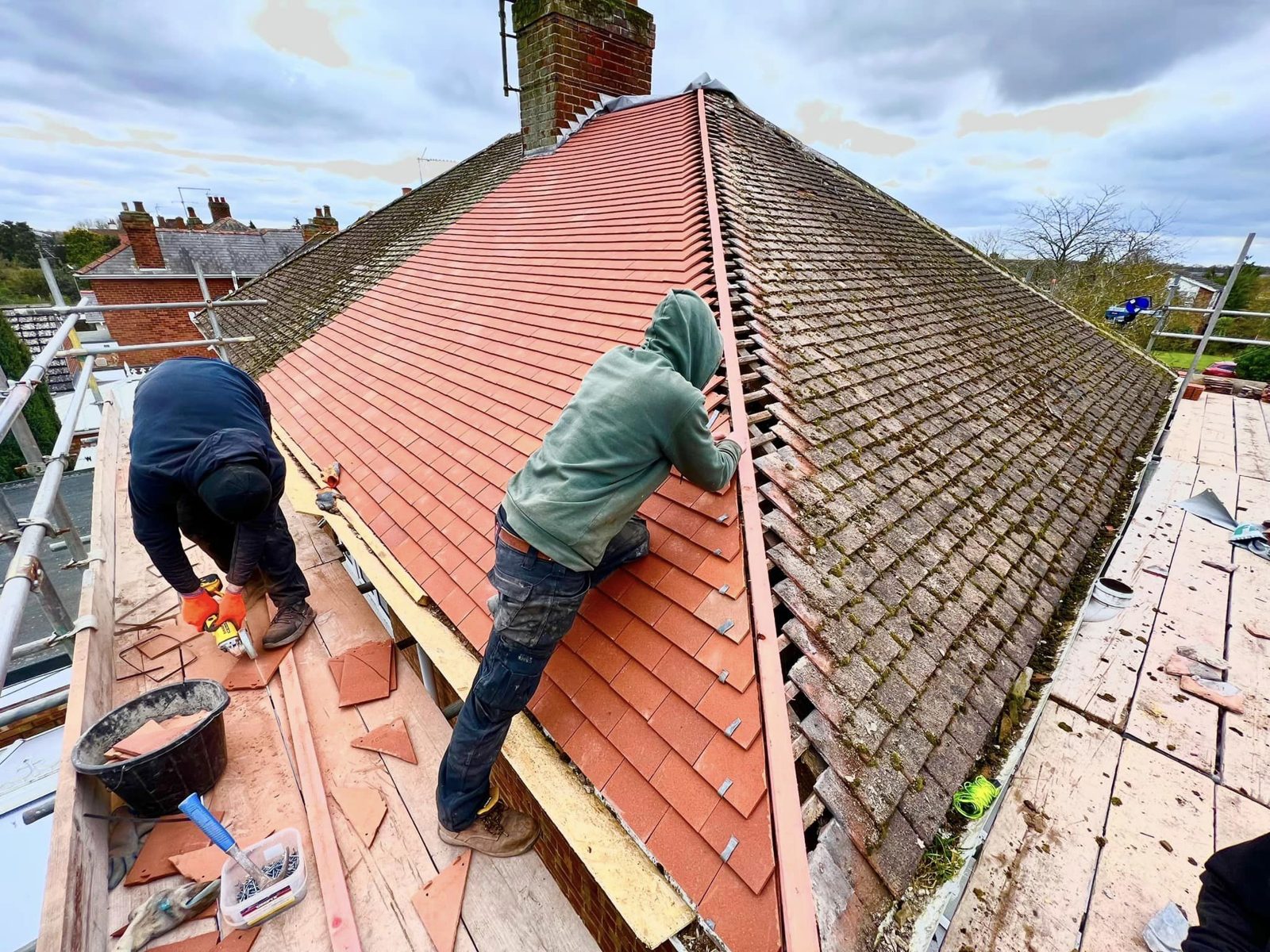 Two Roof Pro roofers re-tiling a pitched roof with new red clay tiles from the scaffold