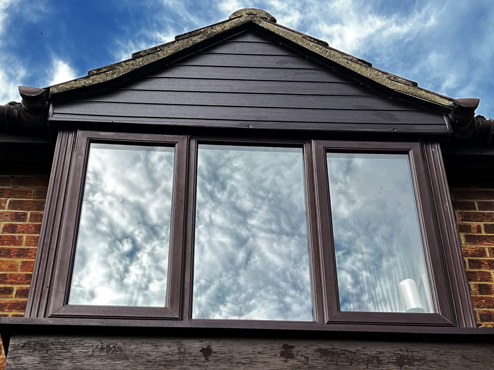 A dormer finished in new dark cladding and fascias above a three-pane window