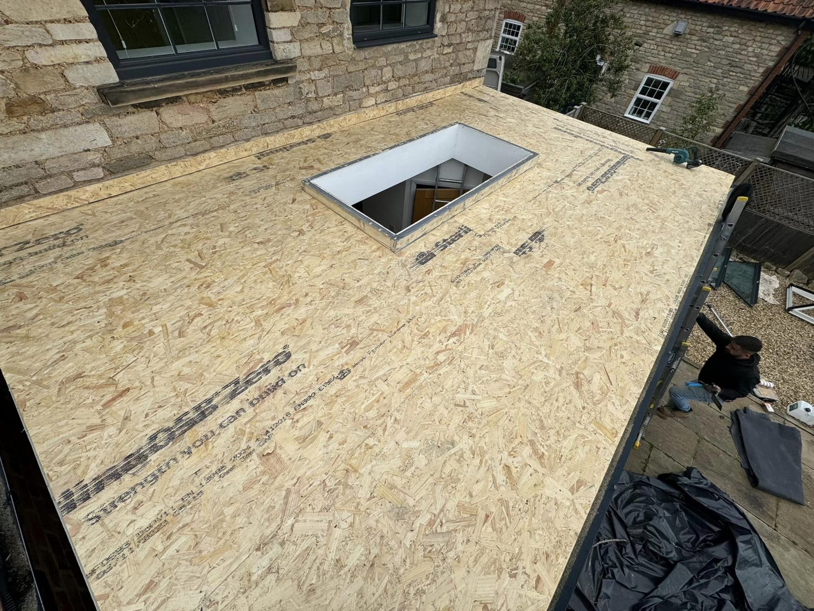 A flat roof extension at deck stage, new boards laid with the opening cut for a roof lantern